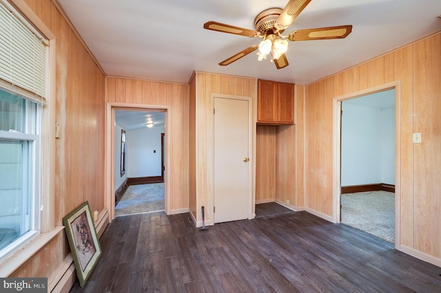 interior space with wood walls, ceiling fan, and dark wood-type flooring