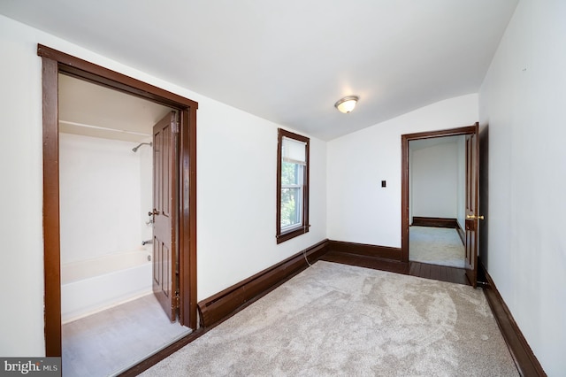 unfurnished bedroom with carpet and lofted ceiling