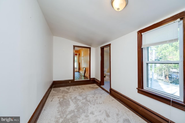 carpeted empty room featuring baseboard heating and vaulted ceiling