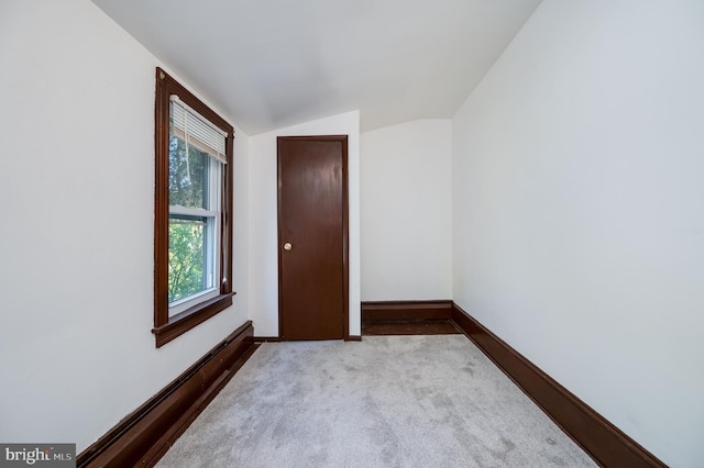 carpeted spare room with a baseboard radiator and lofted ceiling