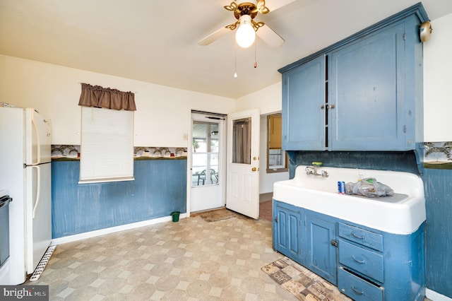 kitchen featuring backsplash, blue cabinets, ceiling fan, and white fridge