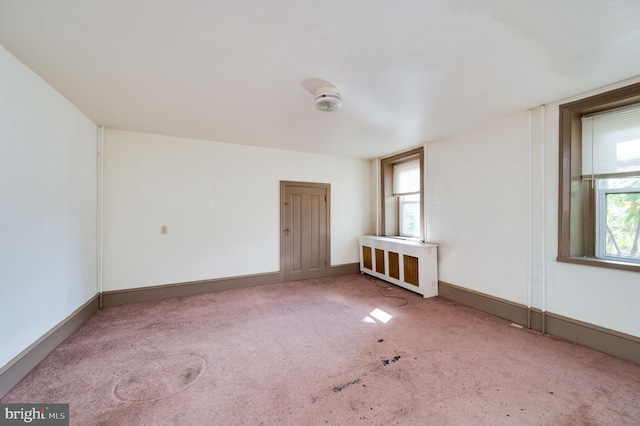 unfurnished room with radiator and carpet flooring