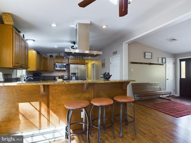 kitchen with vaulted ceiling, island range hood, dark hardwood / wood-style flooring, stainless steel appliances, and ceiling fan