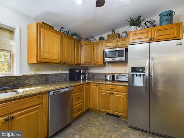 kitchen featuring dark stone countertops, vaulted ceiling, and appliances with stainless steel finishes