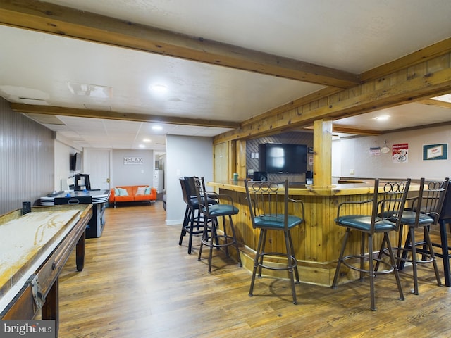 bar featuring beam ceiling, wood walls, and hardwood / wood-style floors