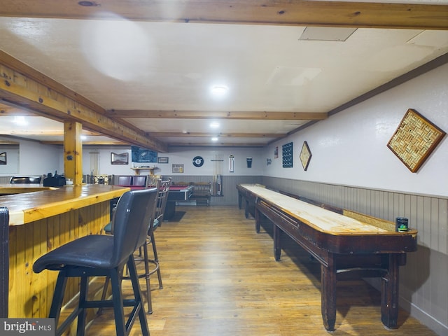 playroom with light wood-type flooring, wood walls, beam ceiling, and indoor bar