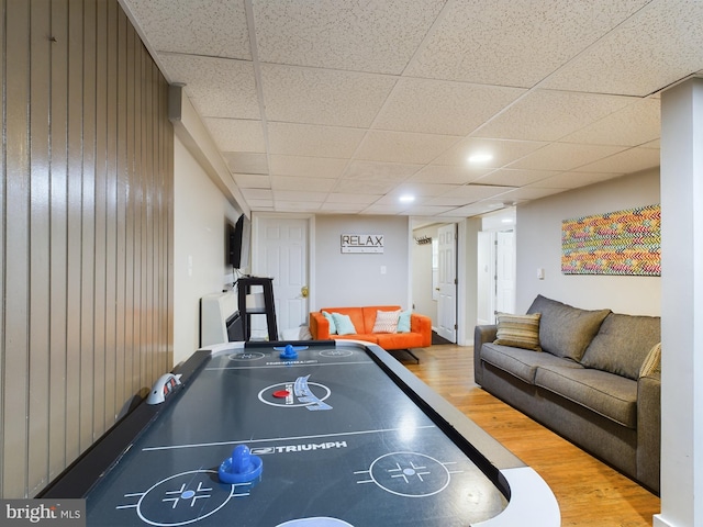 rec room featuring hardwood / wood-style flooring, a drop ceiling, and wood walls