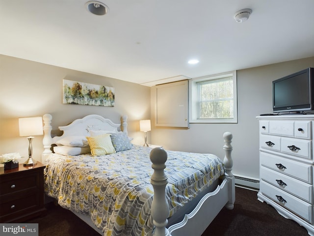 bedroom with dark colored carpet and a baseboard heating unit