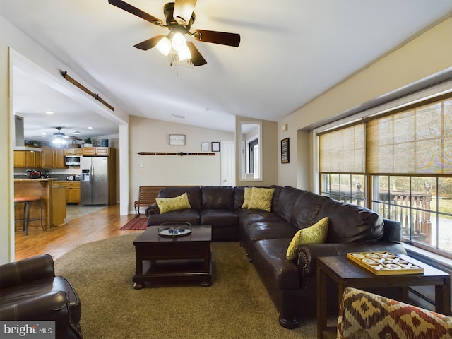 living room featuring ceiling fan, lofted ceiling, and light hardwood / wood-style floors