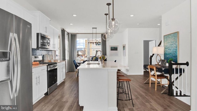 kitchen with white cabinets, an island with sink, dark hardwood / wood-style floors, sink, and stainless steel appliances