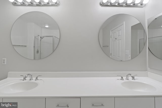 bathroom featuring a shower with door and vanity