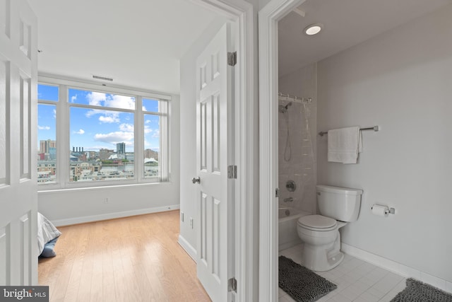 bathroom with shower / tub combo with curtain, hardwood / wood-style floors, and toilet