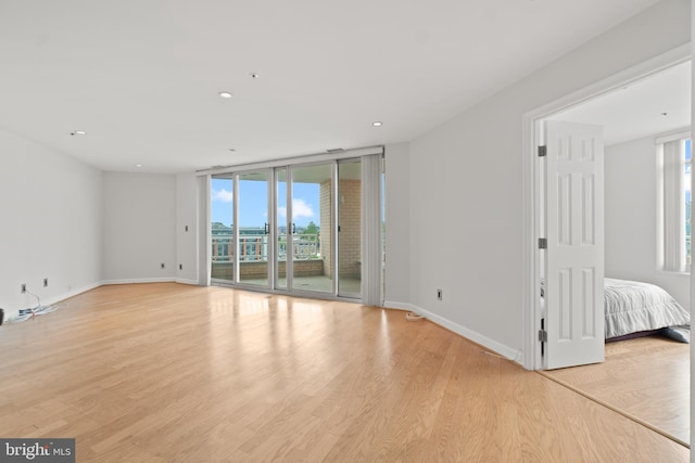 unfurnished room with light hardwood / wood-style flooring, a wealth of natural light, and a wall of windows