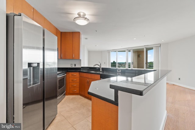 kitchen featuring dark stone countertops, sink, stainless steel appliances, and kitchen peninsula