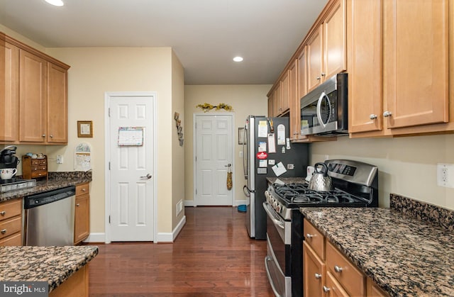 kitchen featuring appliances with stainless steel finishes, dark stone counters, and dark hardwood / wood-style floors