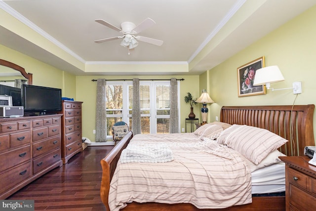 bedroom with ceiling fan, dark hardwood / wood-style floors, crown molding, and a tray ceiling