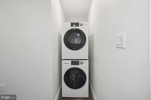 laundry area featuring stacked washer / drying machine and dark hardwood / wood-style floors