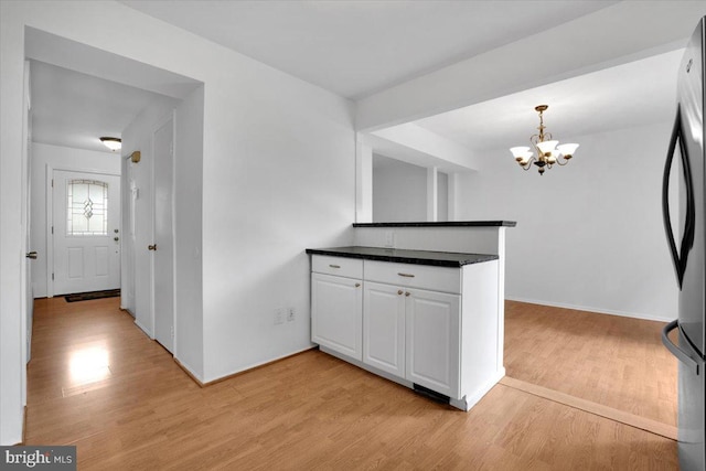 kitchen with white cabinets, a notable chandelier, light wood-type flooring, and pendant lighting