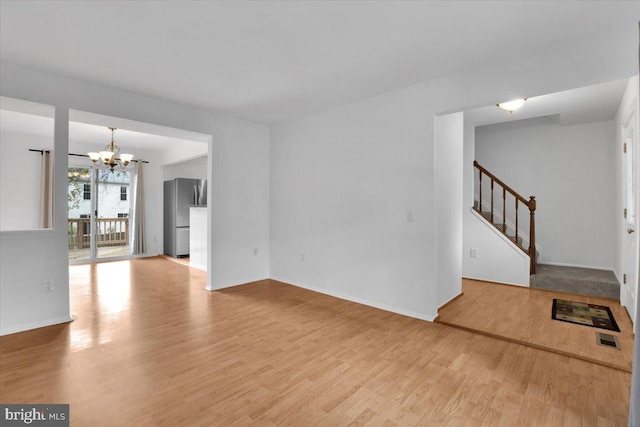 unfurnished living room with light hardwood / wood-style floors and a notable chandelier