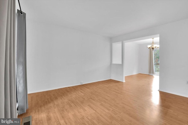 unfurnished room with an inviting chandelier and light wood-type flooring