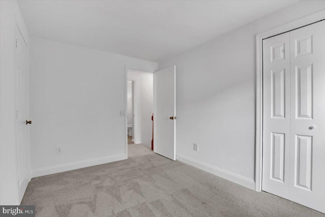 unfurnished bedroom featuring light colored carpet and a closet