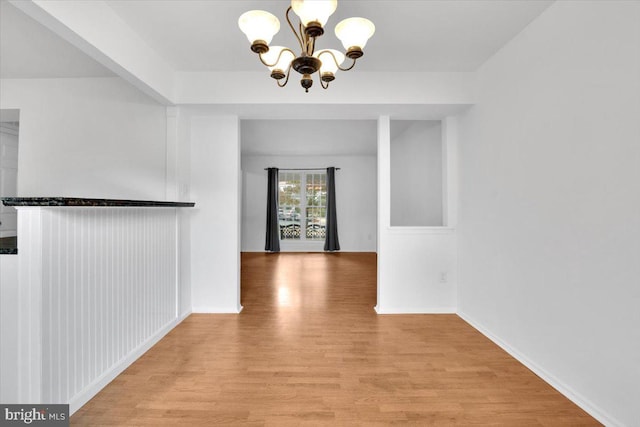 unfurnished dining area with an inviting chandelier and light hardwood / wood-style floors