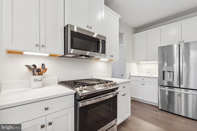 kitchen with stainless steel appliances, white cabinetry, and light hardwood / wood-style floors