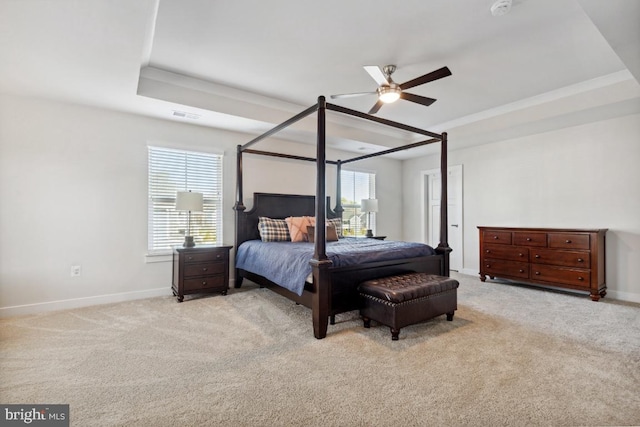 carpeted bedroom with a raised ceiling and ceiling fan