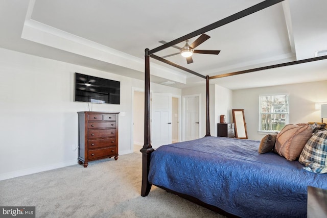 bedroom featuring a raised ceiling, light carpet, and ceiling fan