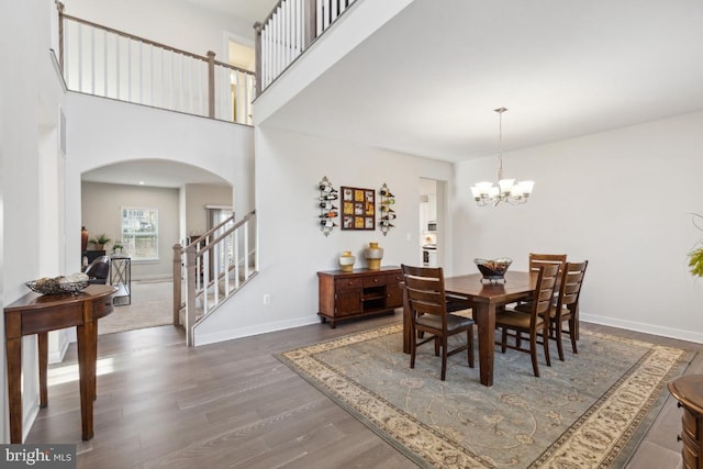 dining area featuring a notable chandelier, a high ceiling, and dark wood-type flooring