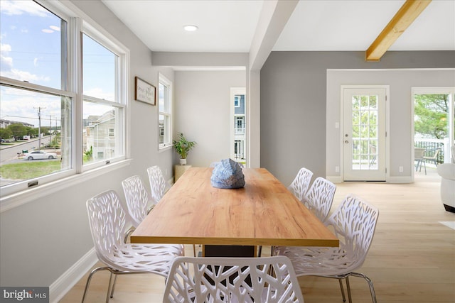 dining room featuring a healthy amount of sunlight, beam ceiling, and light hardwood / wood-style floors