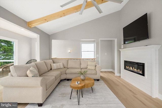 living room featuring ceiling fan, lofted ceiling with beams, light hardwood / wood-style floors, and a healthy amount of sunlight