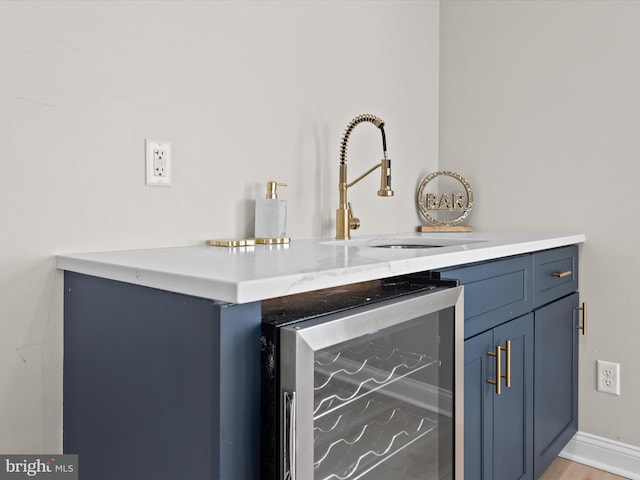 interior space featuring wine cooler, blue cabinets, sink, and light hardwood / wood-style flooring