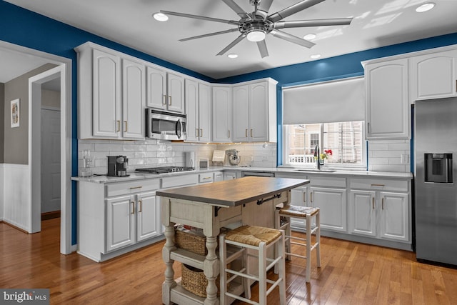 kitchen featuring a kitchen island, white cabinets, light hardwood / wood-style flooring, and stainless steel appliances