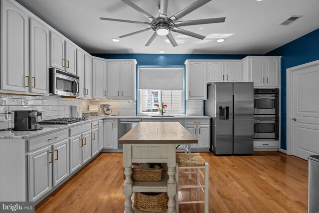 kitchen with sink, white cabinetry, stainless steel appliances, and light wood-type flooring