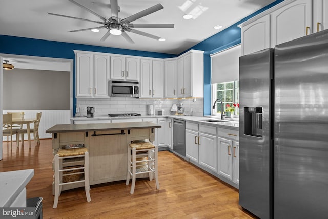 kitchen featuring light hardwood / wood-style flooring, stainless steel appliances, sink, a kitchen bar, and white cabinetry