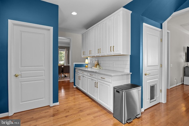 kitchen featuring white cabinetry, tasteful backsplash, stainless steel refrigerator, and light hardwood / wood-style flooring