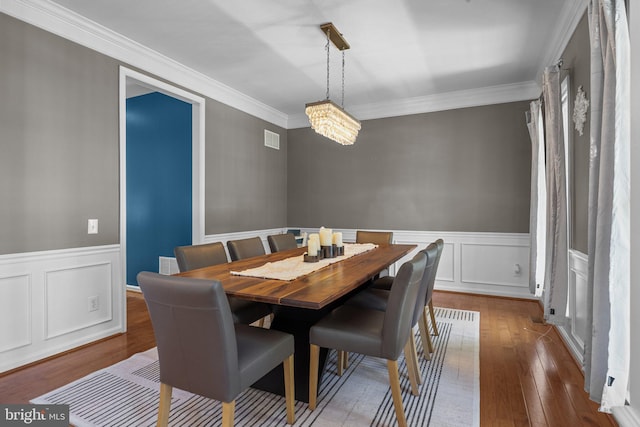 dining space featuring ornamental molding, hardwood / wood-style floors, and a notable chandelier