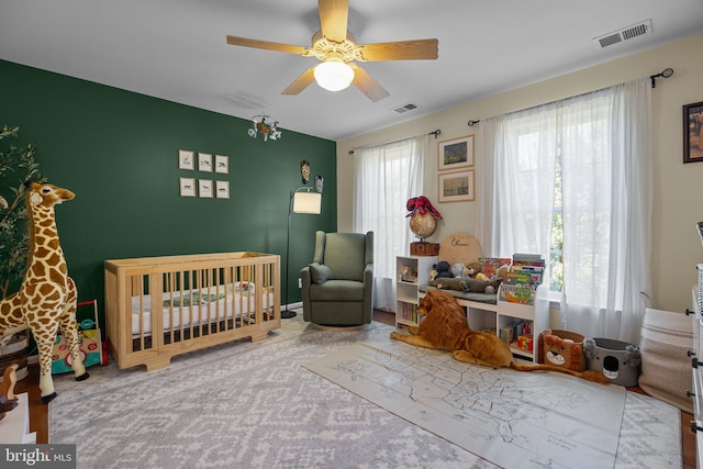 bedroom featuring a nursery area and ceiling fan