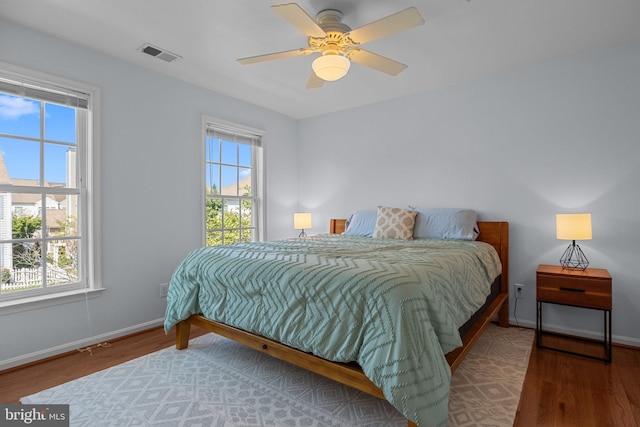 bedroom featuring multiple windows, hardwood / wood-style flooring, and ceiling fan