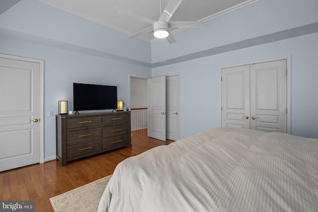 bedroom with dark wood-type flooring, ceiling fan, multiple closets, and ornamental molding