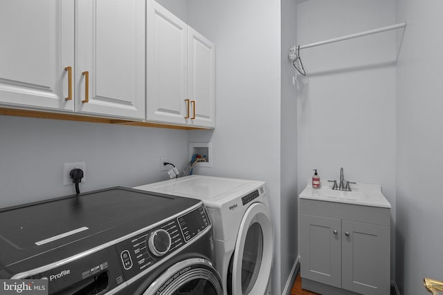 clothes washing area with sink, independent washer and dryer, and cabinets