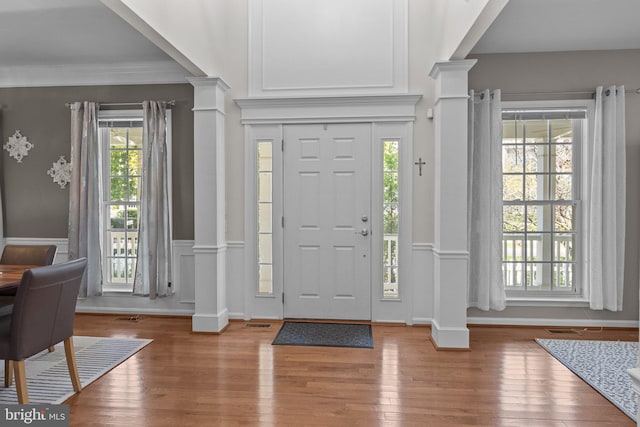 foyer featuring wood-type flooring and ornate columns