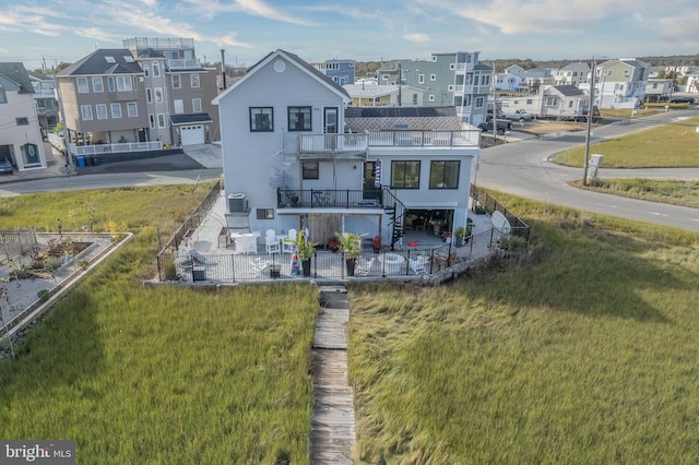 rear view of property with a residential view, fence, a balcony, and a lawn