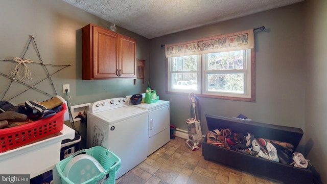 clothes washing area with a textured ceiling, washer and clothes dryer, and cabinets