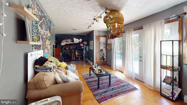 living room featuring track lighting, a textured ceiling, and wood-type flooring