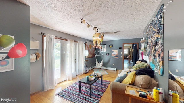 living room featuring light hardwood / wood-style flooring, a textured ceiling, track lighting, and a baseboard radiator