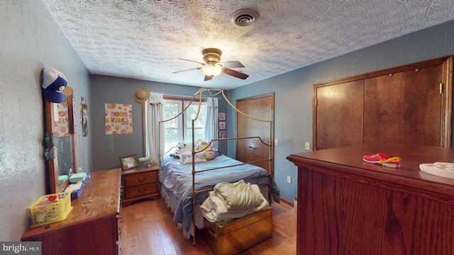 bedroom featuring ceiling fan, a textured ceiling, and light hardwood / wood-style flooring