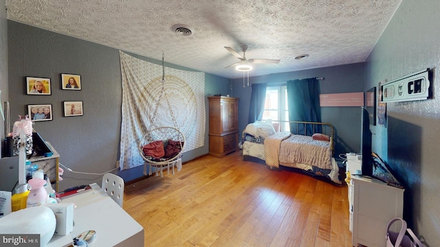 bedroom with light hardwood / wood-style floors, a textured ceiling, and ceiling fan