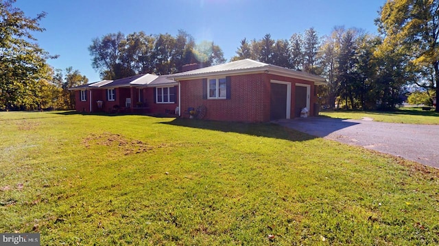 view of home's exterior featuring a garage, a yard, brick siding, and aphalt driveway
